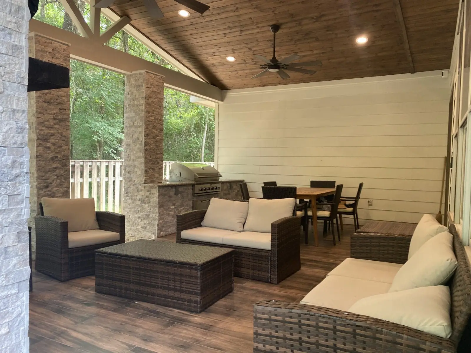 Cozy covered patio with wicker furniture and ceiling fans.