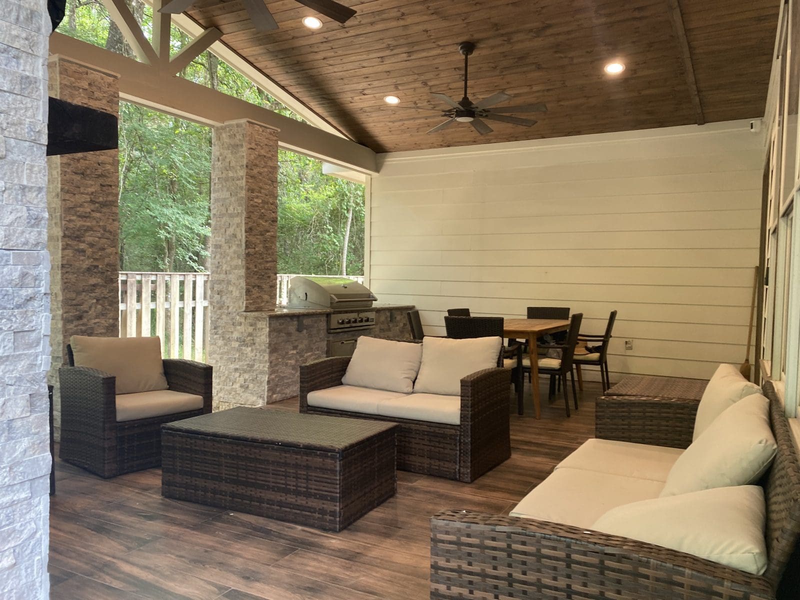 Cozy covered patio with wicker furniture and ceiling fans.