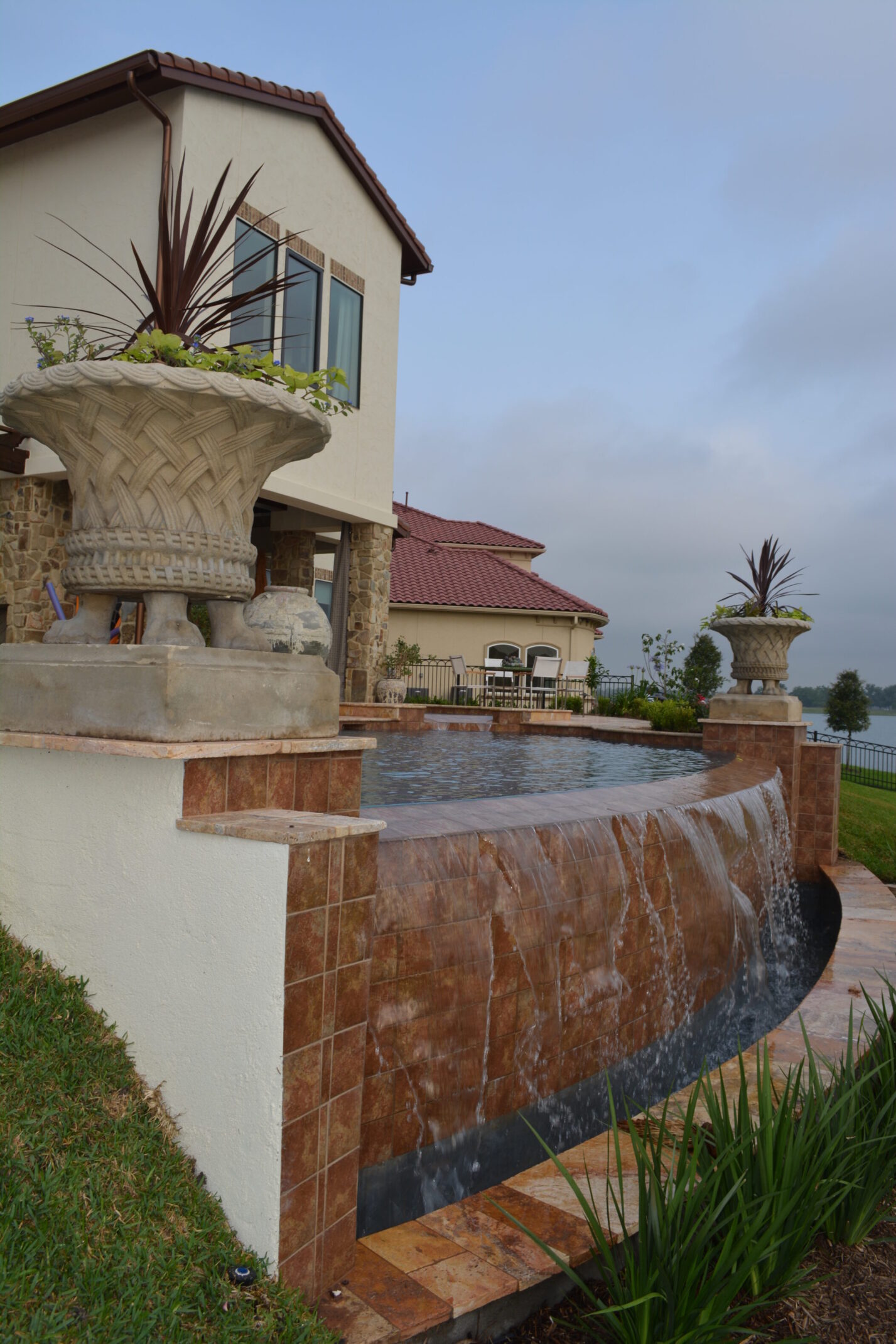 Infinity pool with cascading waterfall and planters at AISD Showcase Home in The Woodlands by JM Outdoor Living