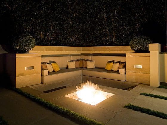 Modern sunken fire pit with built-in seating and accent lighting in The Woodlands TX
