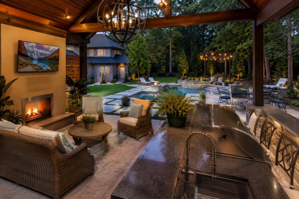 JM Outdoor Living custom outdoor living space with covered patio, outdoor kitchen, pool, and landscape lighting in The Woodlands, TX.